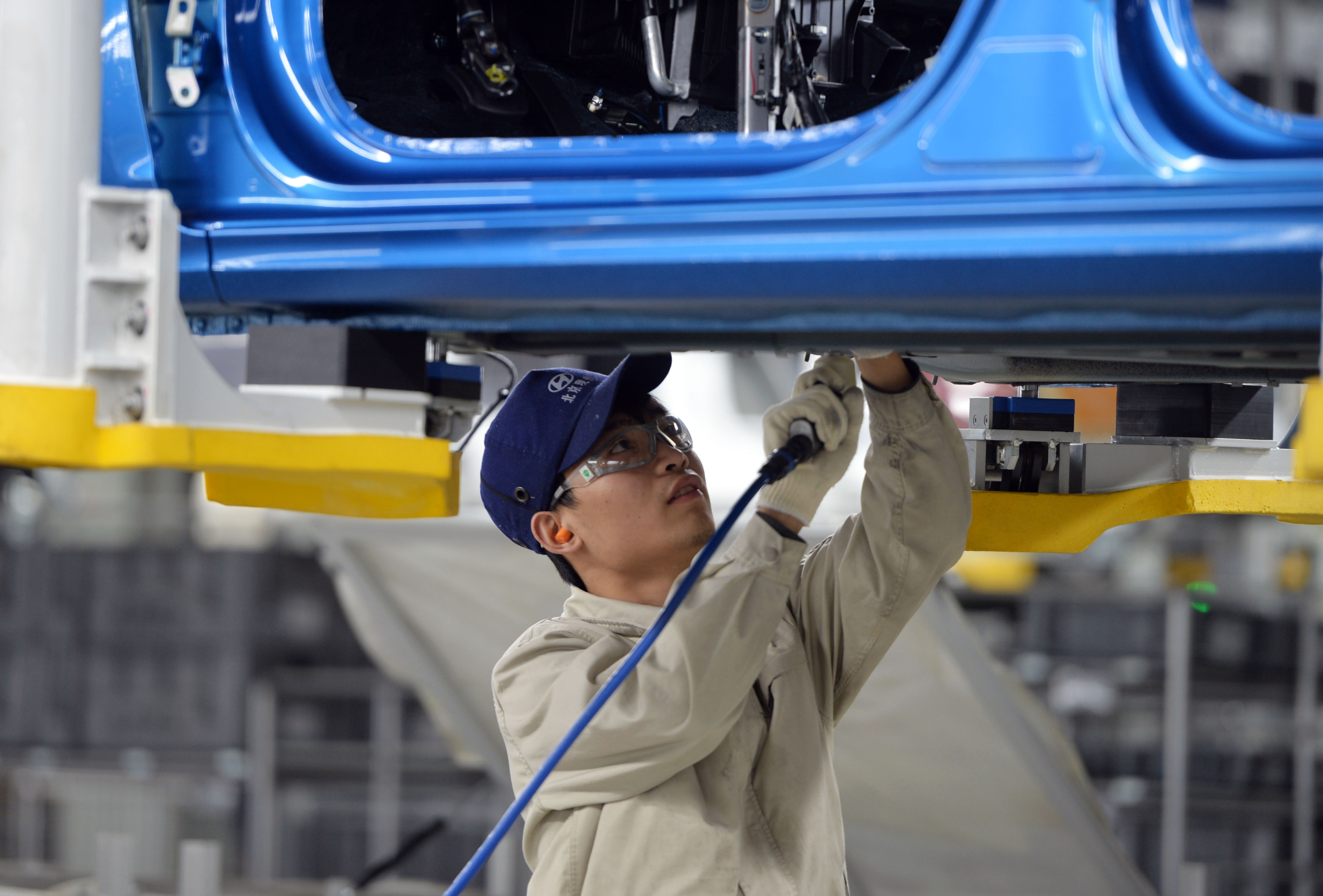 A worker in Hyundai's Cangzhou factory in China tightens screws on a vehicle.