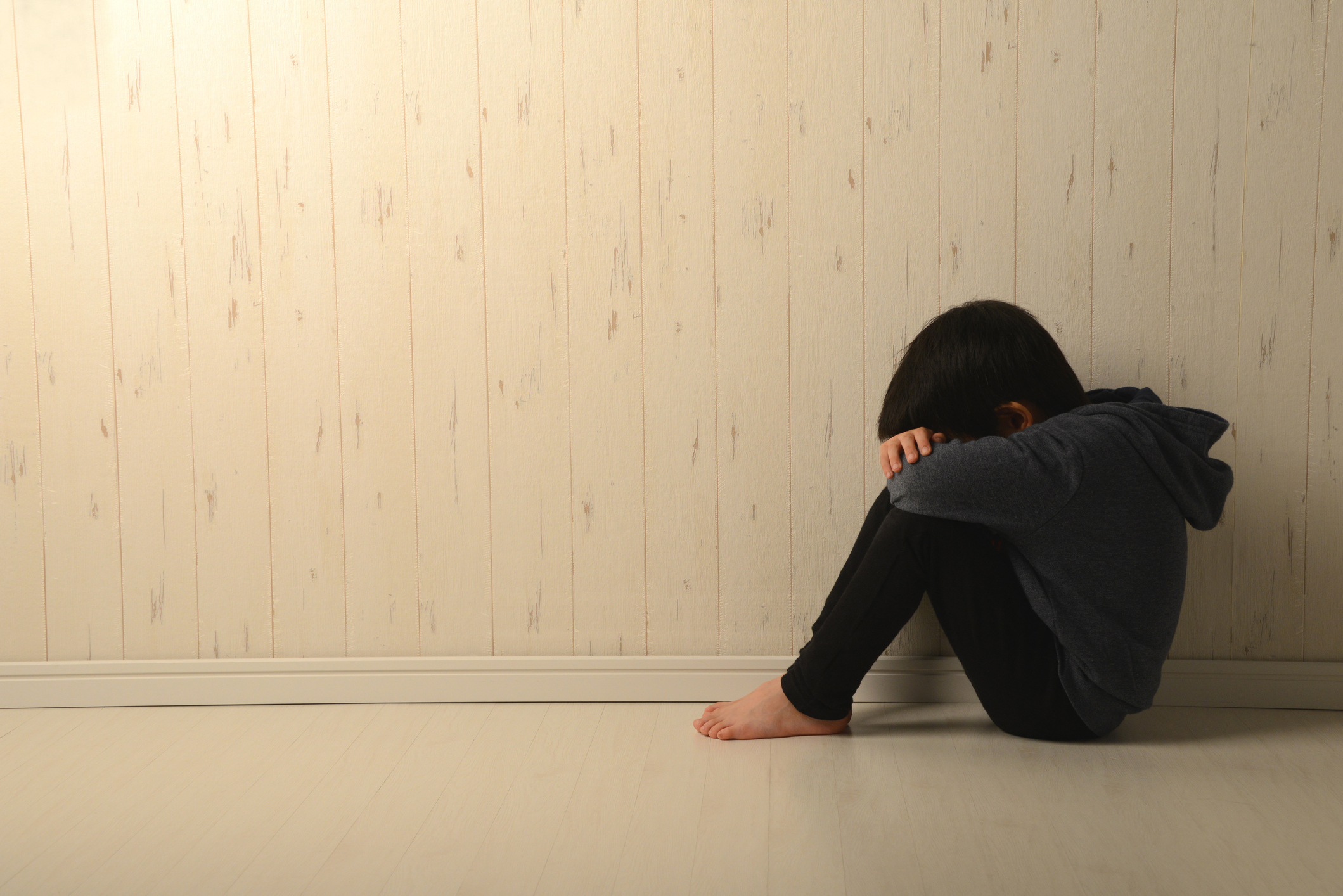 Suffering child in dark room - stock photo