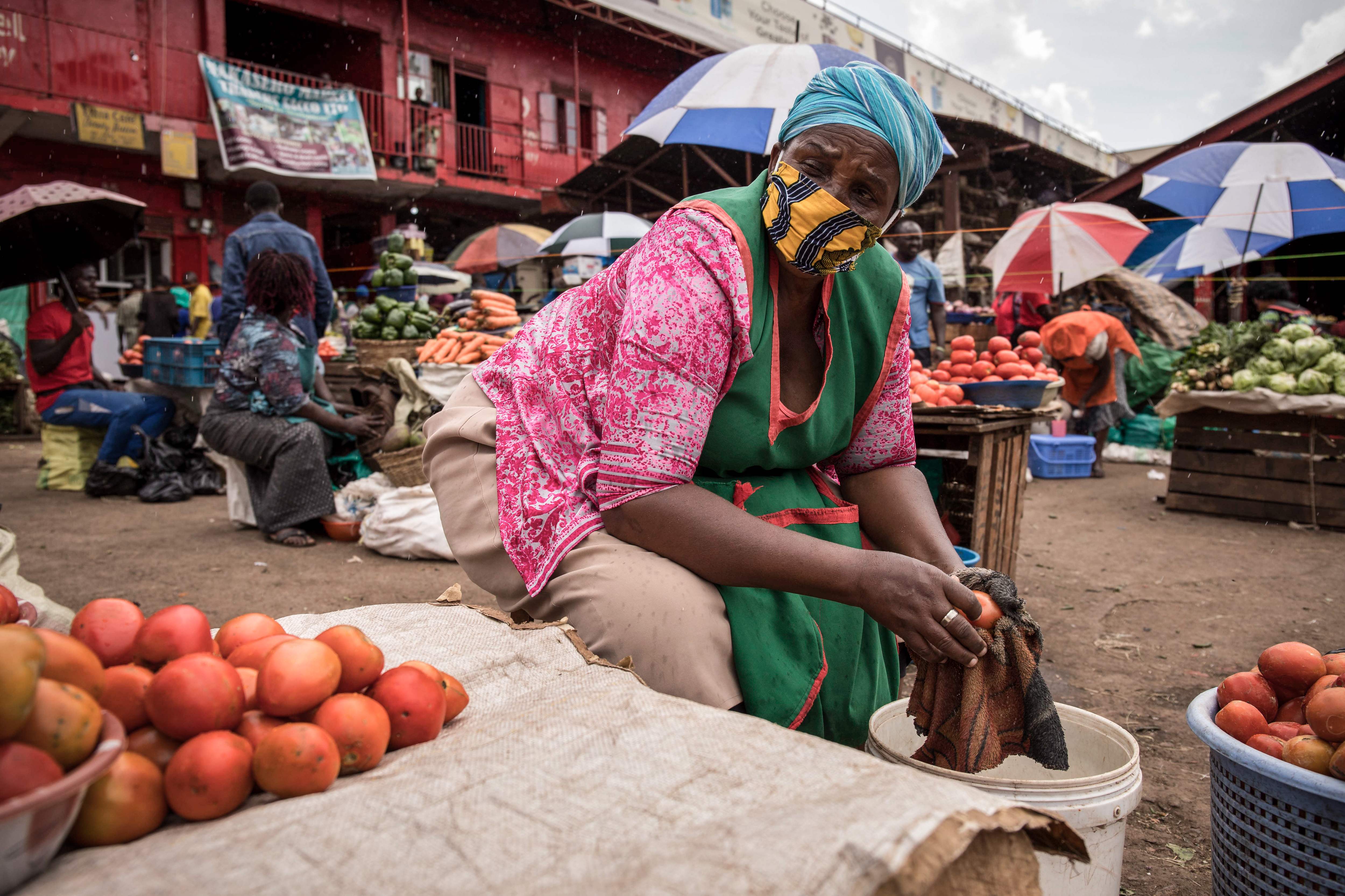 Eine Frau verkauft Tomaten mit einer Gesichtsmaske auf dem Nakasero-Markt in Kampala, Uganda.