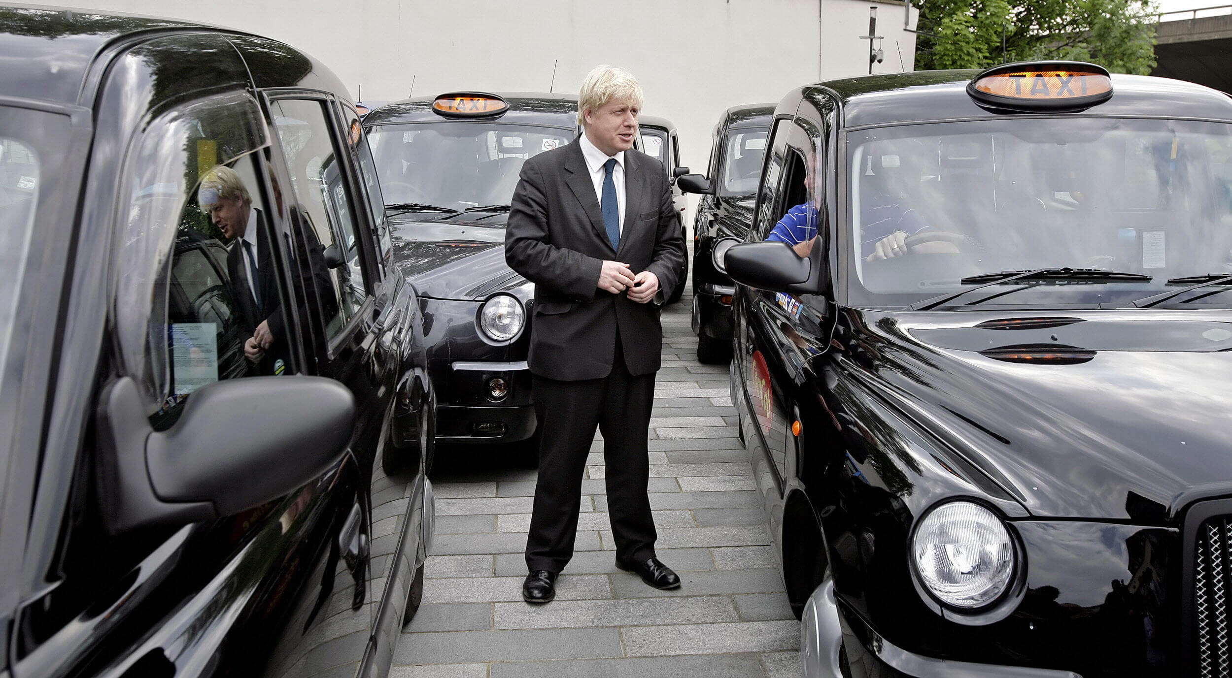 Boris Johnson standing next to iconic London Black Cabs in 2008, at the time a newly elected Mayor of London