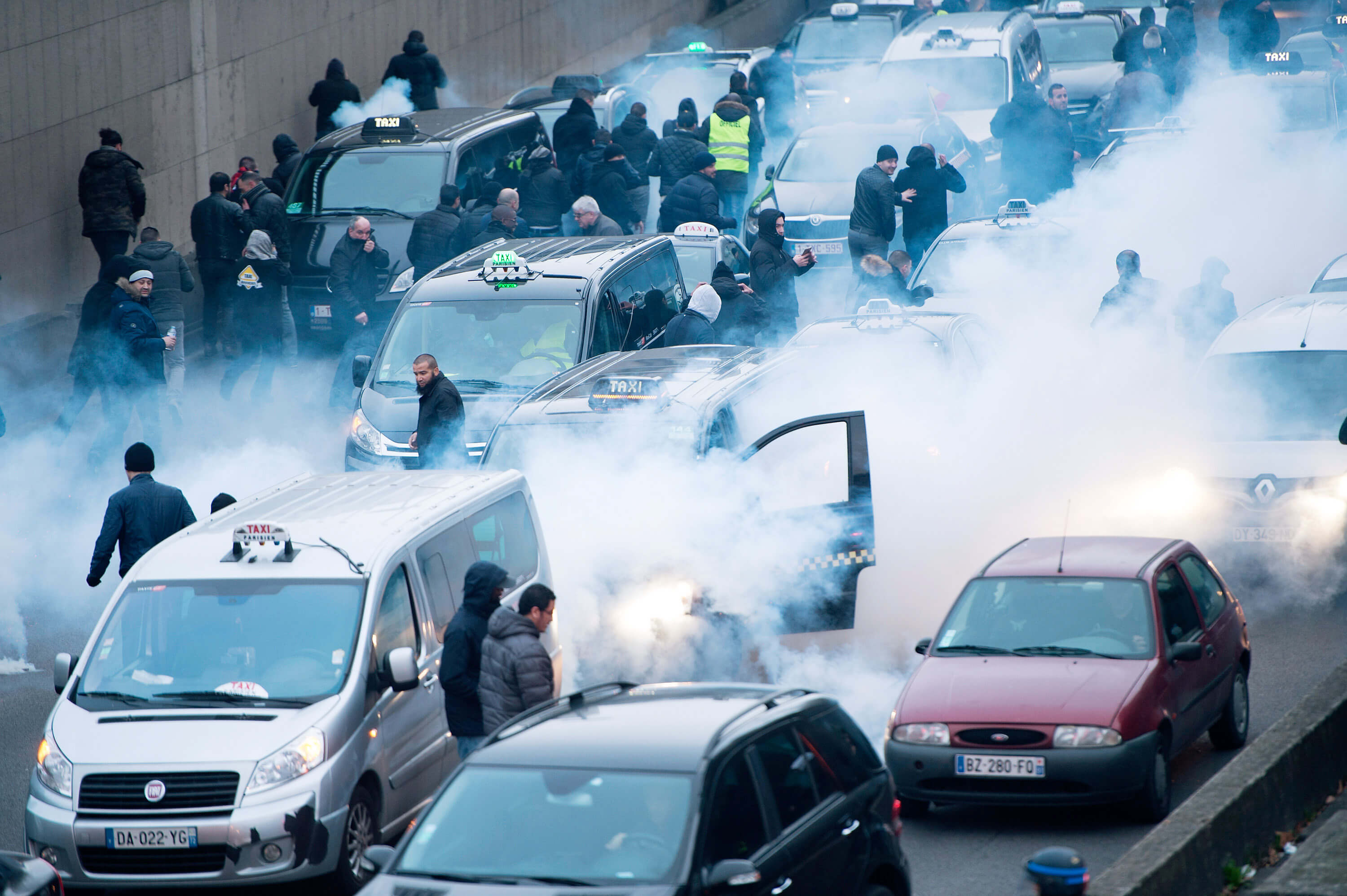 Riot police use tear gas as taxi drivers demonstrate by blocking the traffic on the peripherique by setting tires on fire, on January 26, 2016 in Paris, France.
