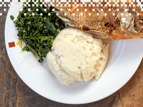 Plato de ugali servido con pescado y hojas de col