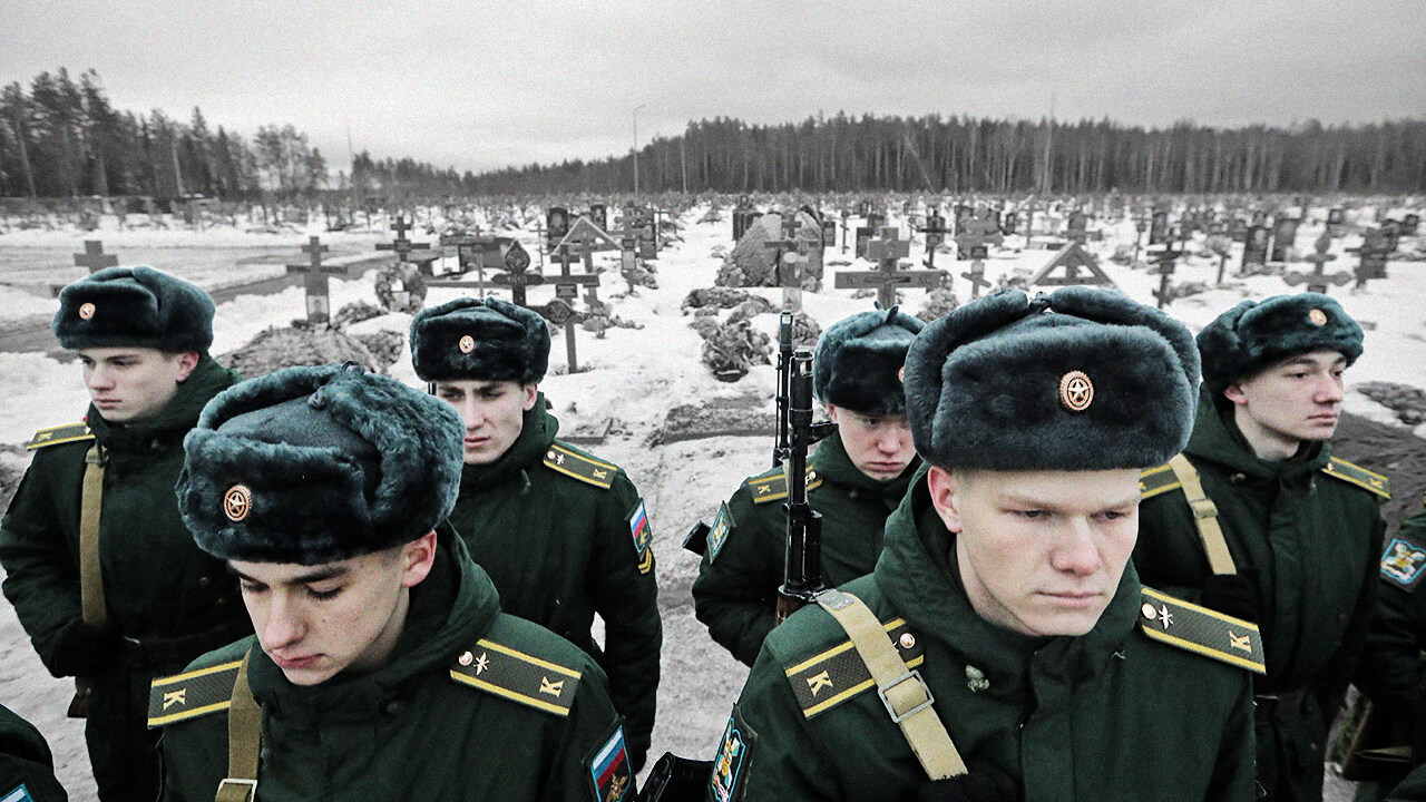 Image of Russian soldiers standing in front of a series of cross-shaped headstones in a cemetery