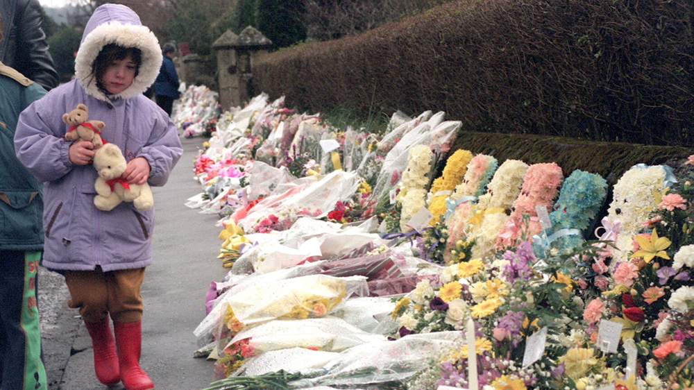 A child lays teddy bears at a memorial in Dunblane in 1996 (Picture: Getty Images)