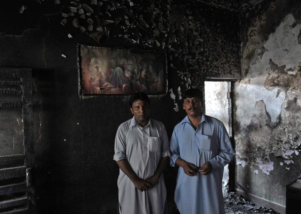 Two Pakistani Christians stand in their burnt-out house in Gojra, 2009