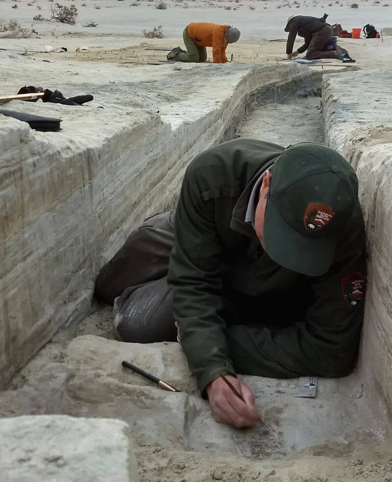 Pesquisador analisando pegadas de mais de 20 mil anos atrás encontradas nas margens de um lago no Novo México.