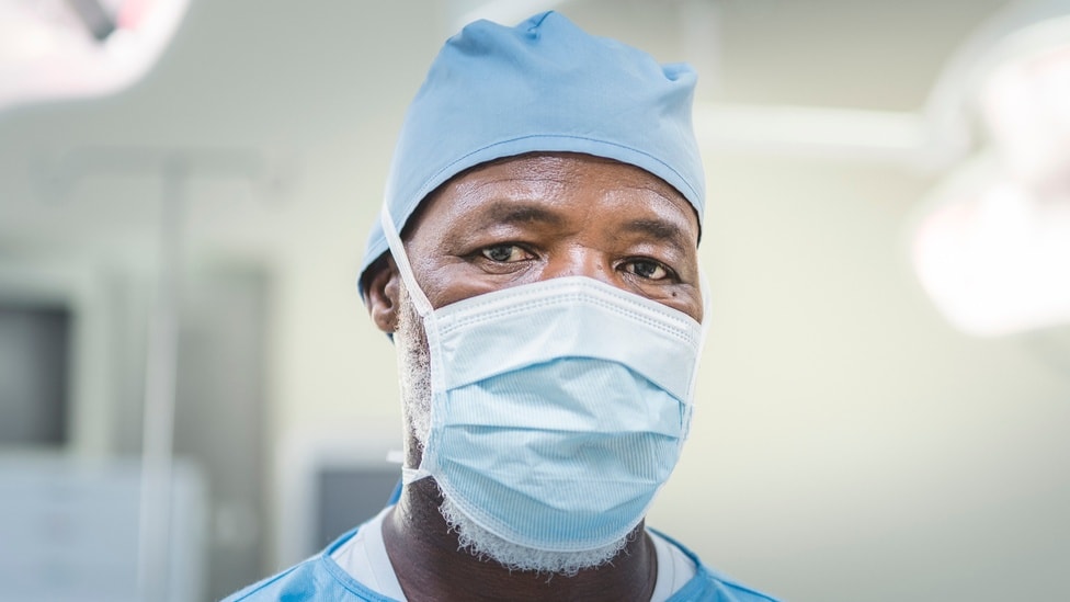 A male surgeon wearing a blue mask