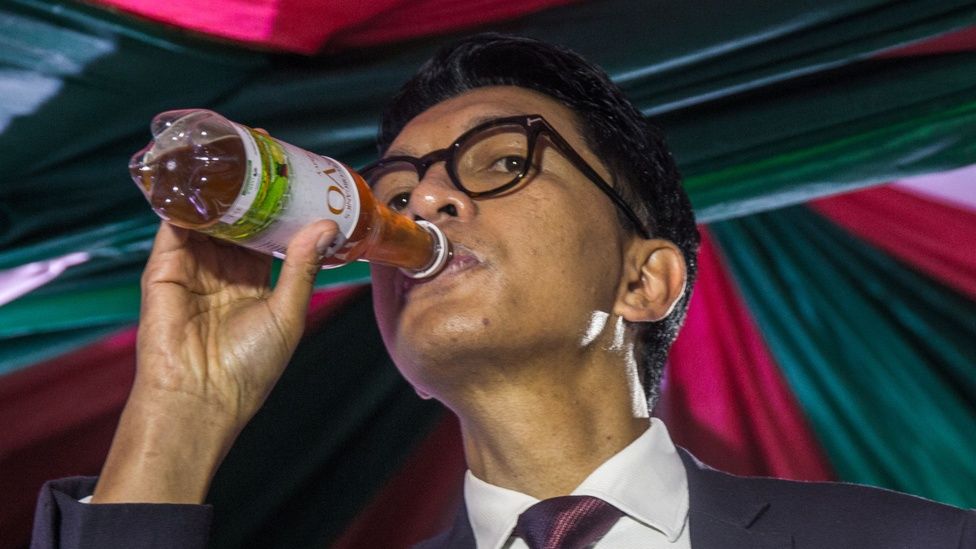 President Rajoelina drinks from a bottle of Covid Organics herbal remedy